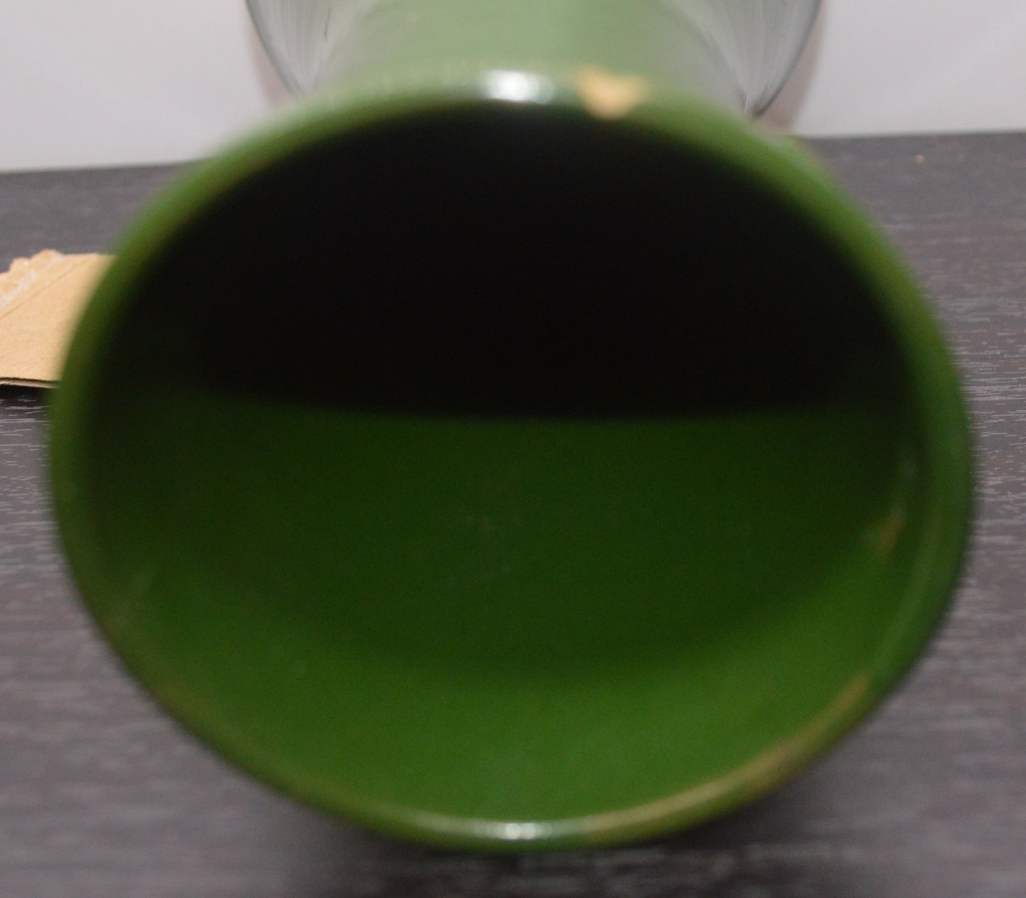 Bottom-up view into a dark green ceramic vase lying