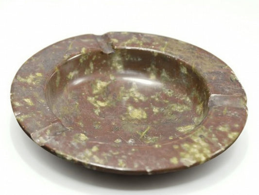 Polished brown natural stone ashtray with green speckled pattern and three cigarette rests, round decorative smoking tray on white background