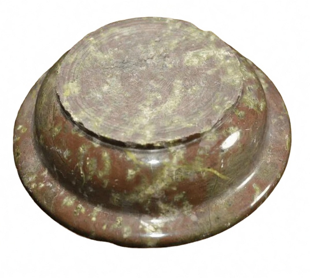 Underside of polished brown natural stone ashtray showing raw base and green speckled pattern, solid round smoking tray detail