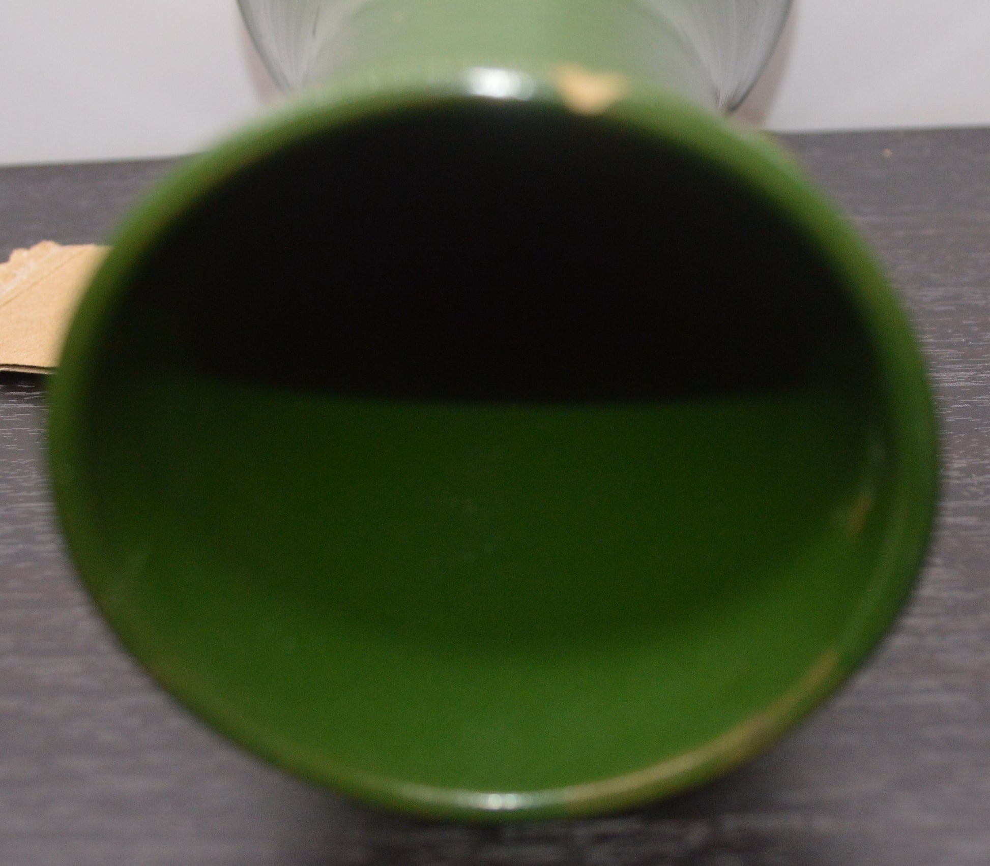 Bottom-up view into a dark green ceramic vase lying