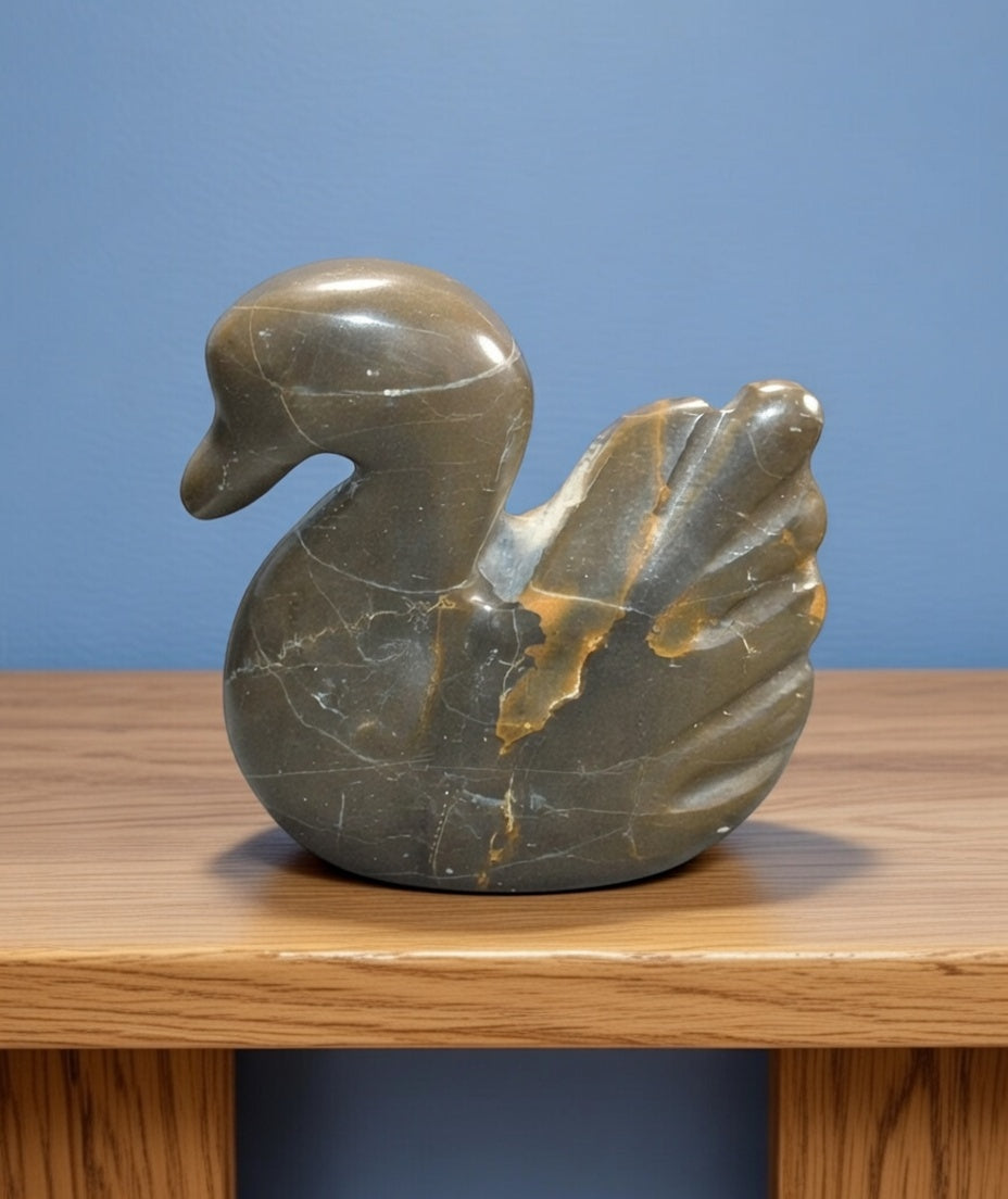 Polished dark stone swan figurine with natural veining and carved wing detail, decorative natural rock bird ornament displayed on wooden shelf.