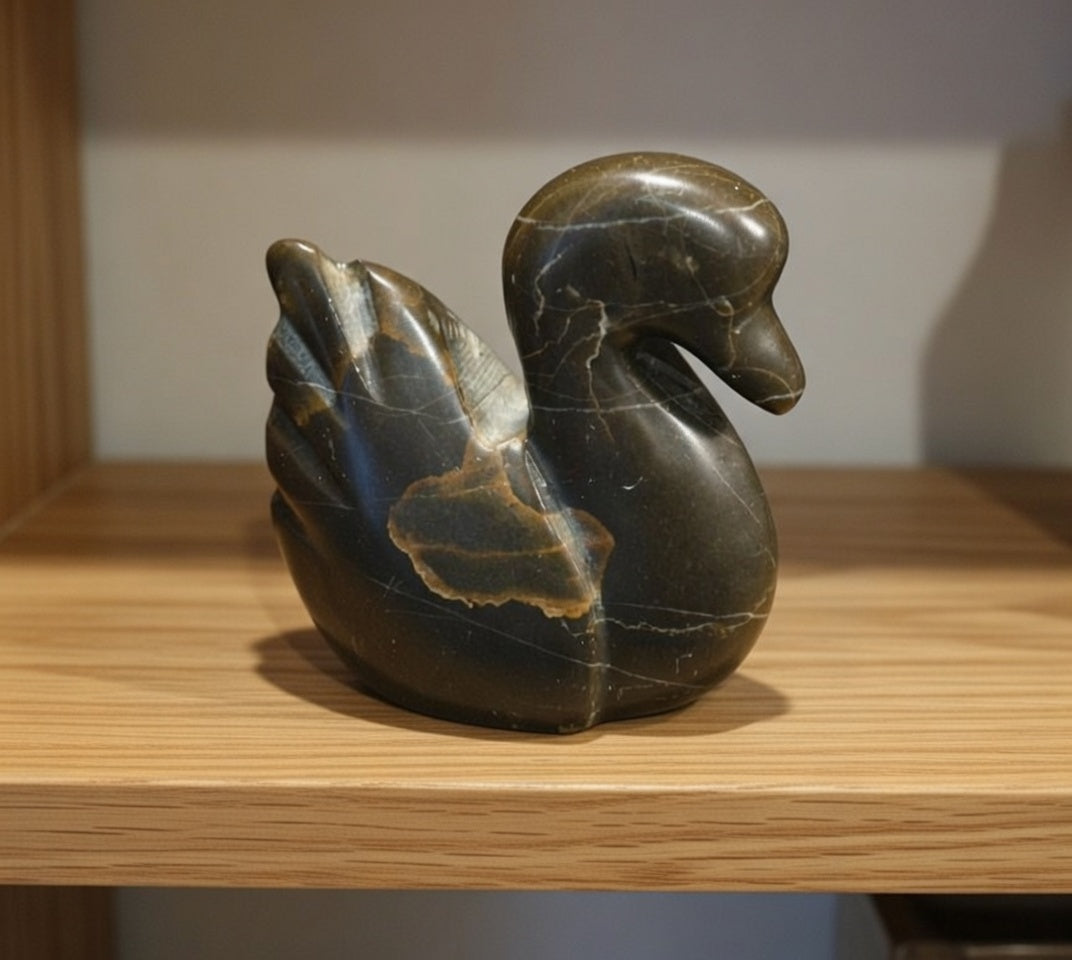Polished stone swan figurine with natural veining and carved wing detail, decorative rock bird ornament displayed on wooden shelf.