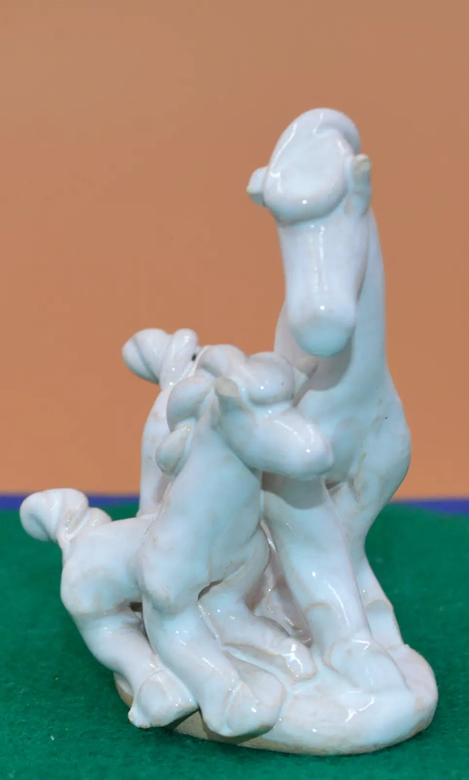 Front view of a white ceramic figurine depicting two abstract, stylized horses